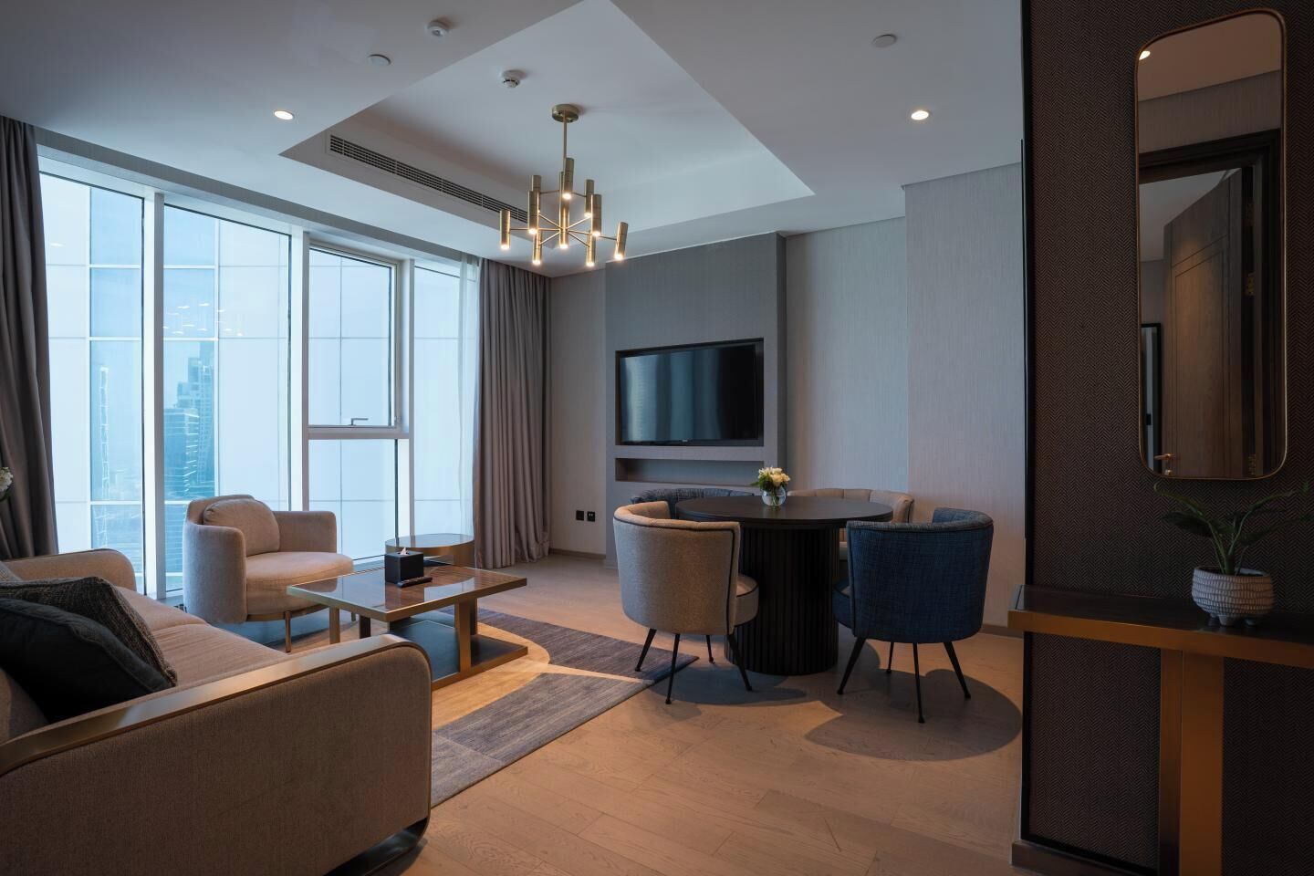 Una sala de estar moderna con un sofá, sillas, una mesa de centro, un televisor y un comedor.