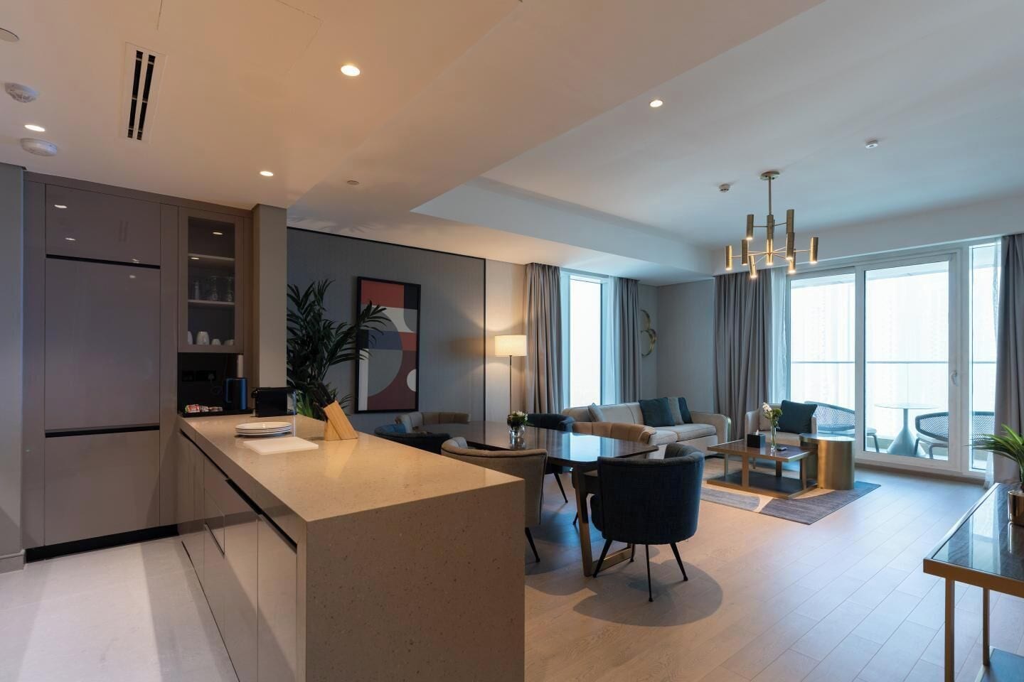Una habitación de hotel moderna con cocina, comedor y un balcón con vistas.