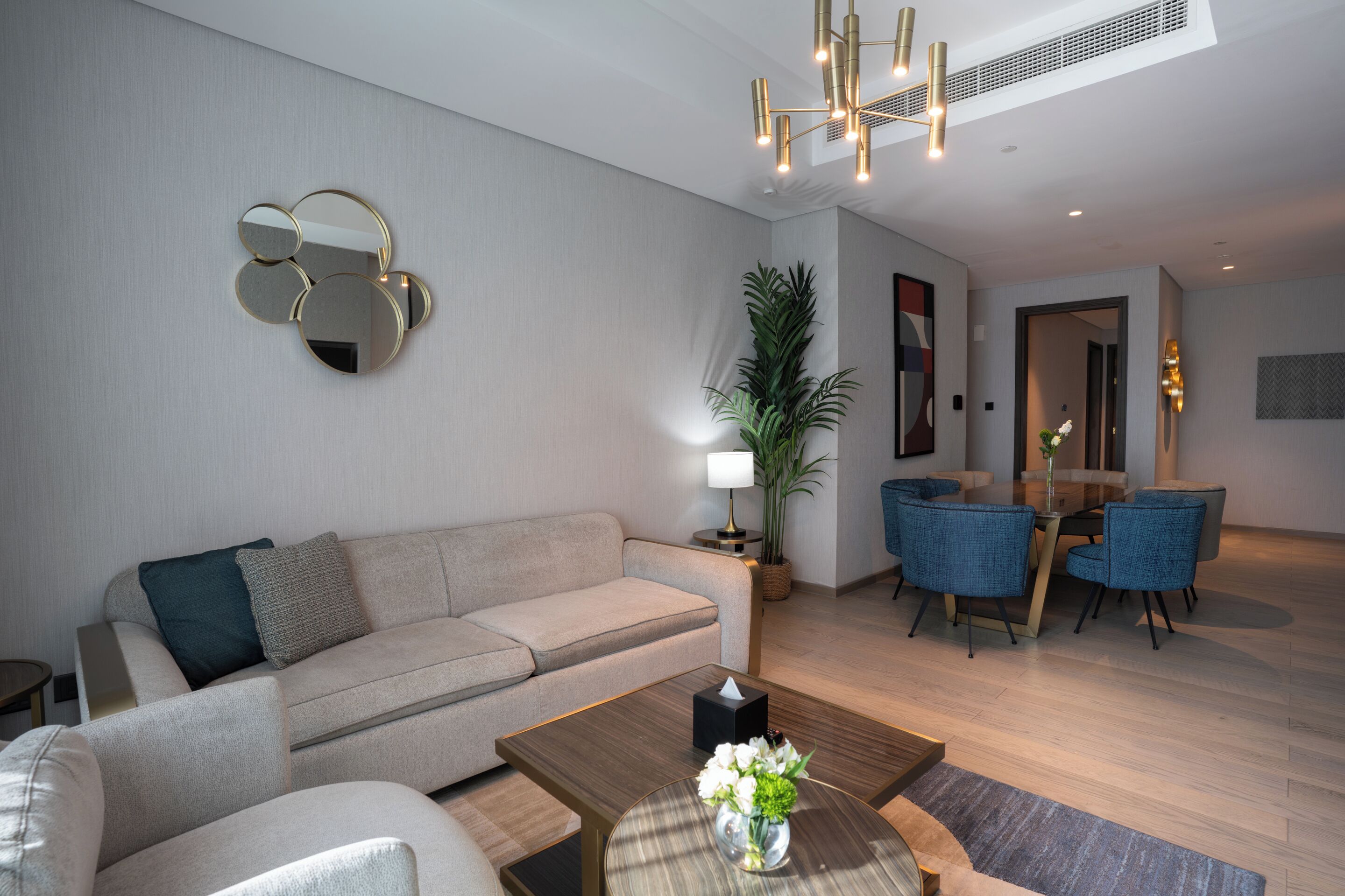 Un salon moderne comprenant un canapé, une table basse et un coin repas avec des chaises.