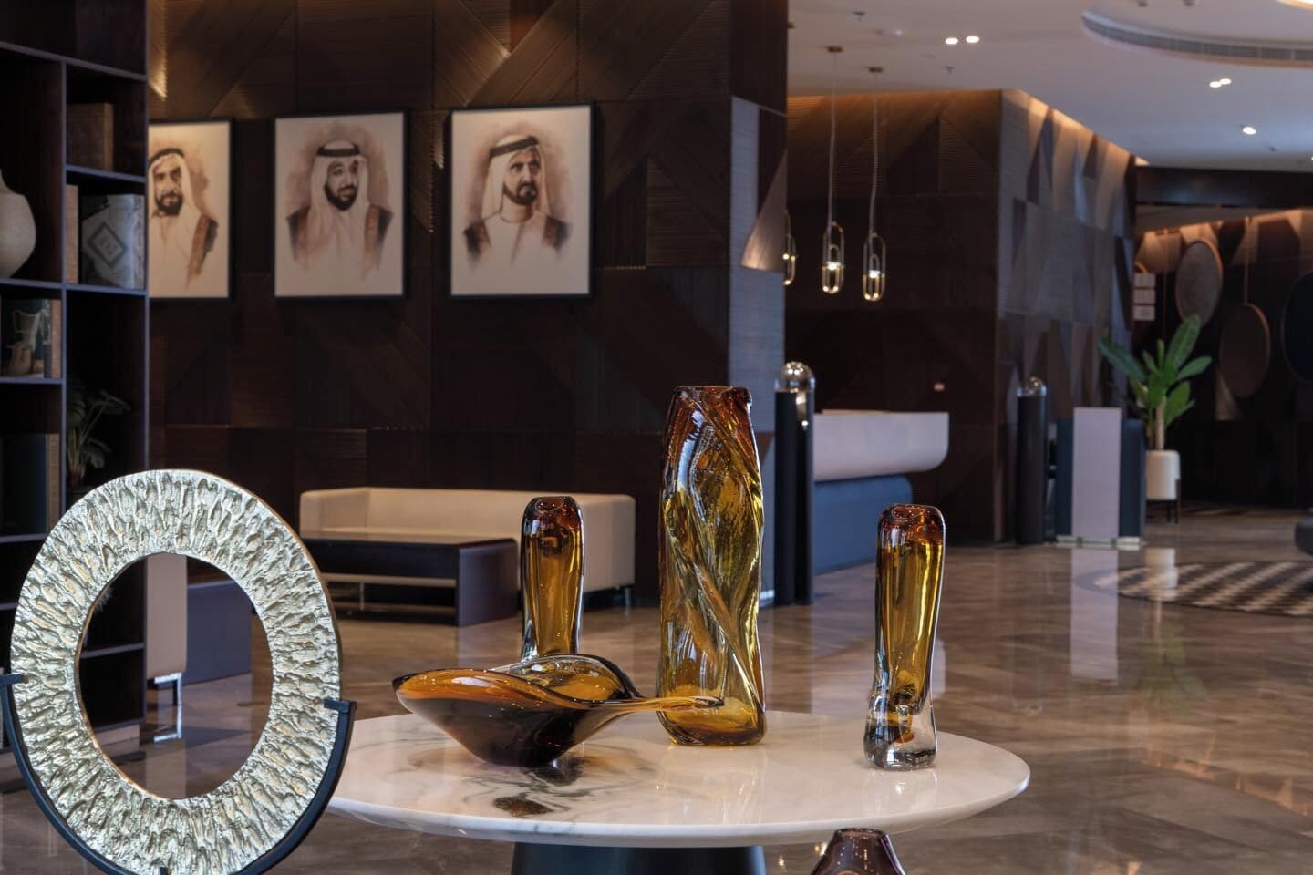 A lobby with a marble table, abstract art, and framed portraits on the wall.