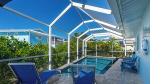 Una piscina exterior techada con sillas azules y vistas claras de los edificios circundantes.