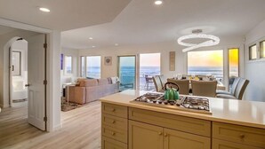 Ett modernt kök med en gasspis, utsikt över havet och en matplats med fin utsikt.