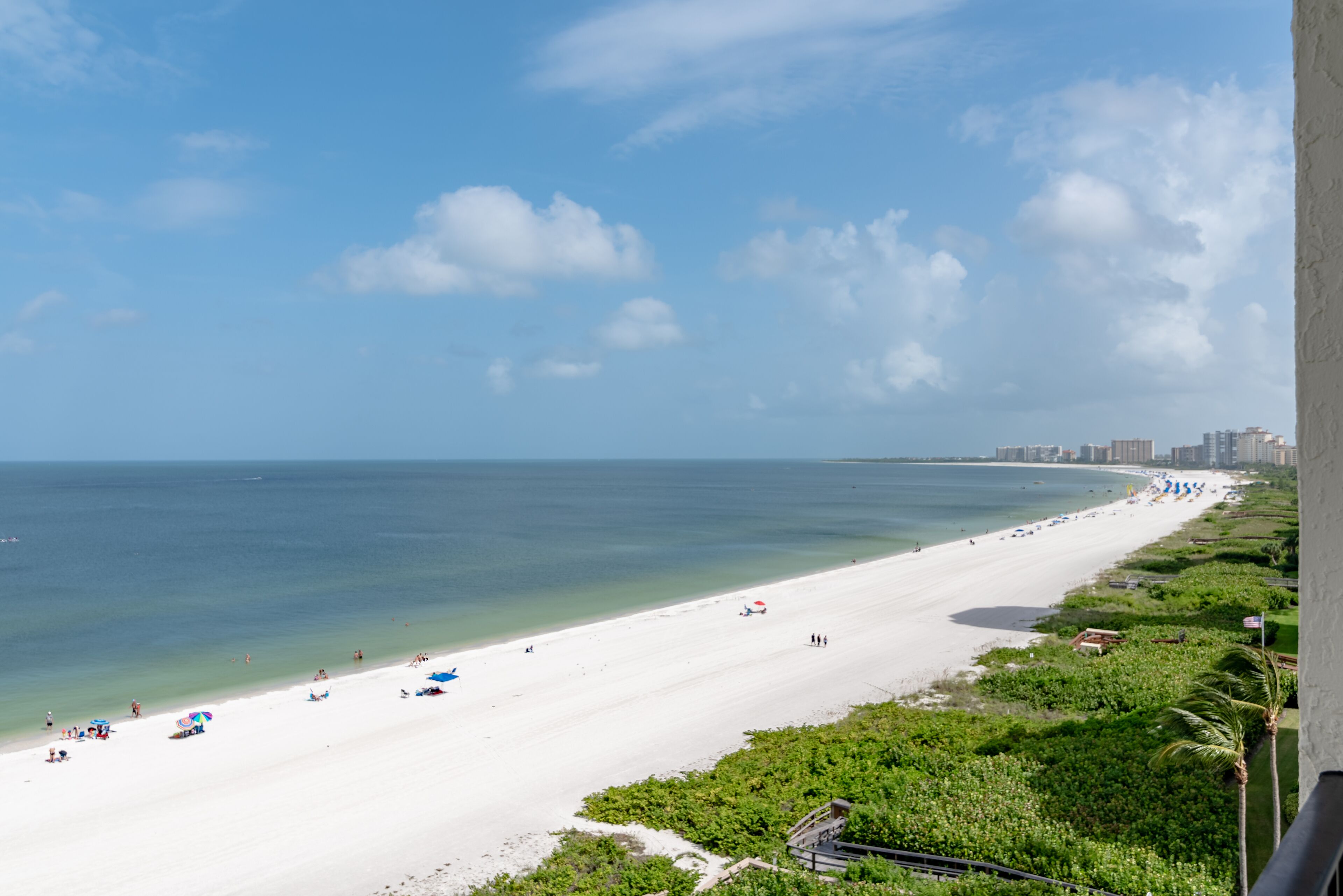 A beach with a clear sky, a sandy shore, and a few umbrellas.