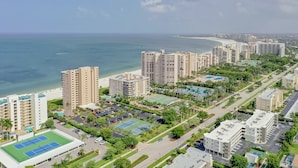 A high-rise hotel with multiple floors, a parking lot, and a tennis court.