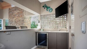 A compact kitchen with a built-in refrigerator, a stone wall, and a small seating area with wicker chairs. - 3 Sprunt Pond at The Sea Pines Resort (Hilton Head Island)