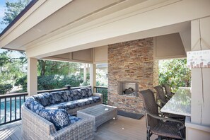 A covered outdoor seating area with a stone fireplace, wicker furniture, and a view of the surrounding greenery. - 3 Sprunt Pond at The Sea Pines Resort (Hilton Head Island)