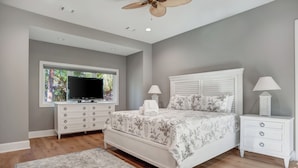 A bedroom with a bed, a TV, a nightstand, and a window with a view of greenery. - 3 Sprunt Pond at The Sea Pines Resort (Hilton Head Island)