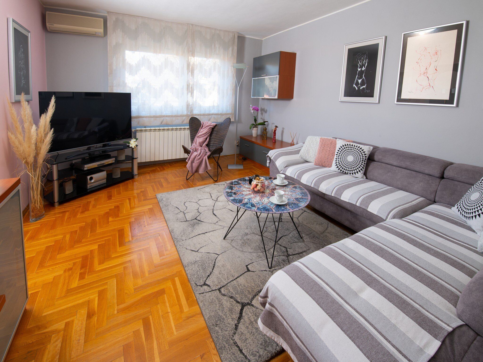 A modern living room with a sofa, a coffee table, a TV, and a fireplace.