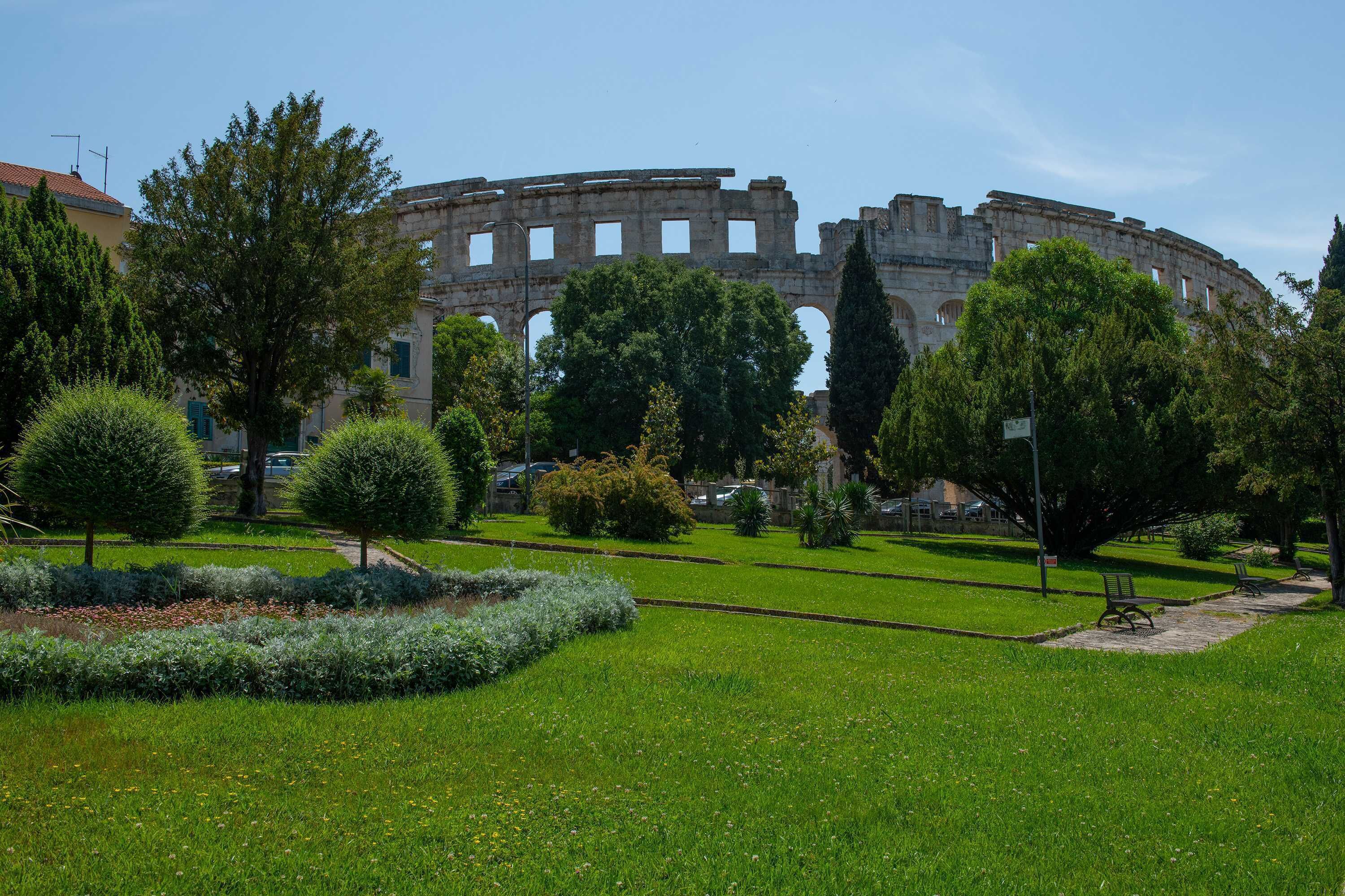 A park with a historic amphitheater in the background.