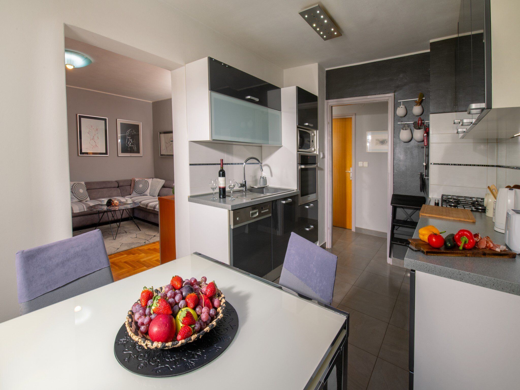 A modern kitchen with a dining area, featuring a fruit bowl on the table.