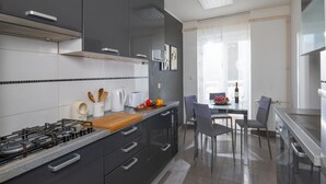 Una cocina moderna con armarios oscuros, una estufa a gas y una tabla de cortar de madera.