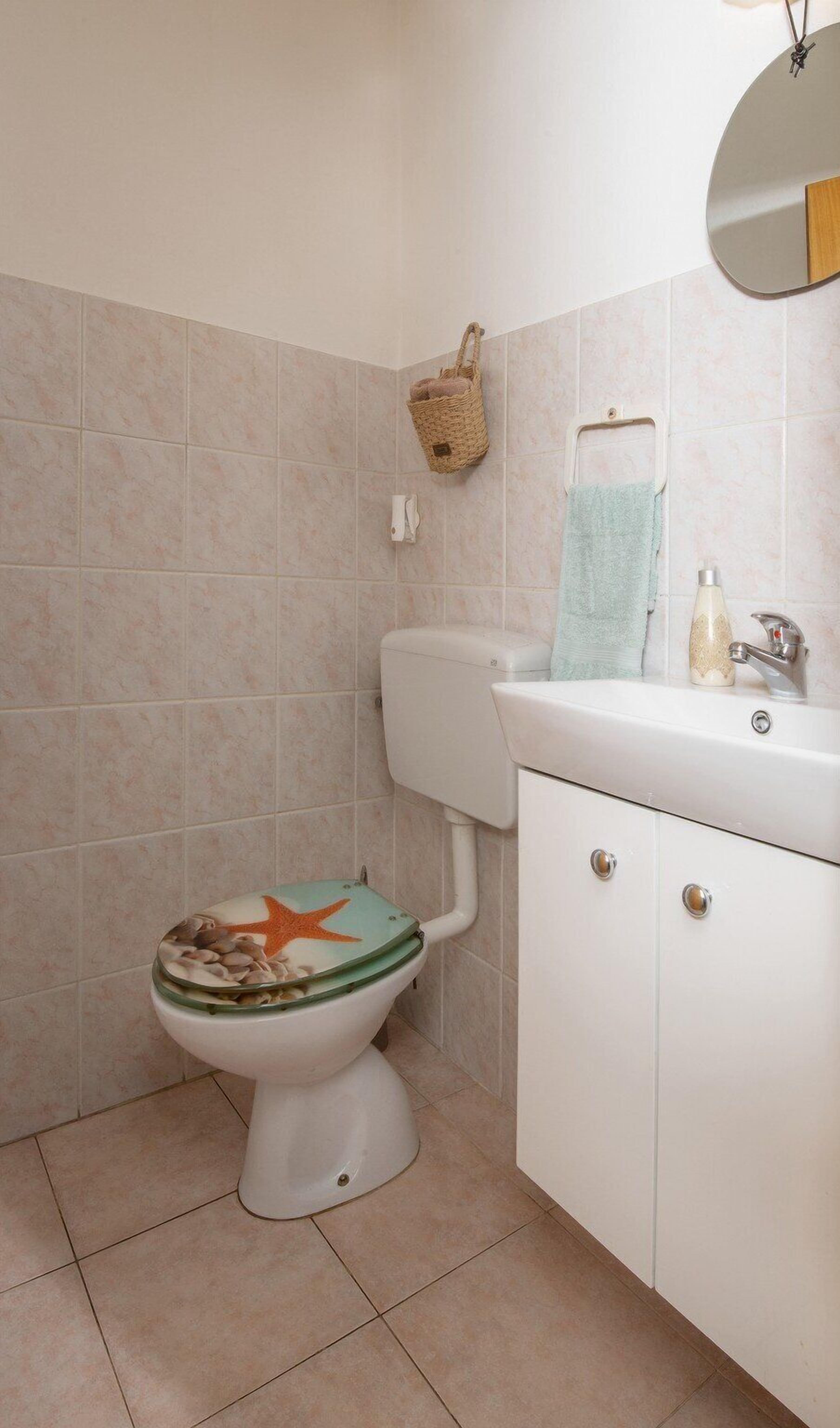 A bathroom with a toilet, sink, and mirror.