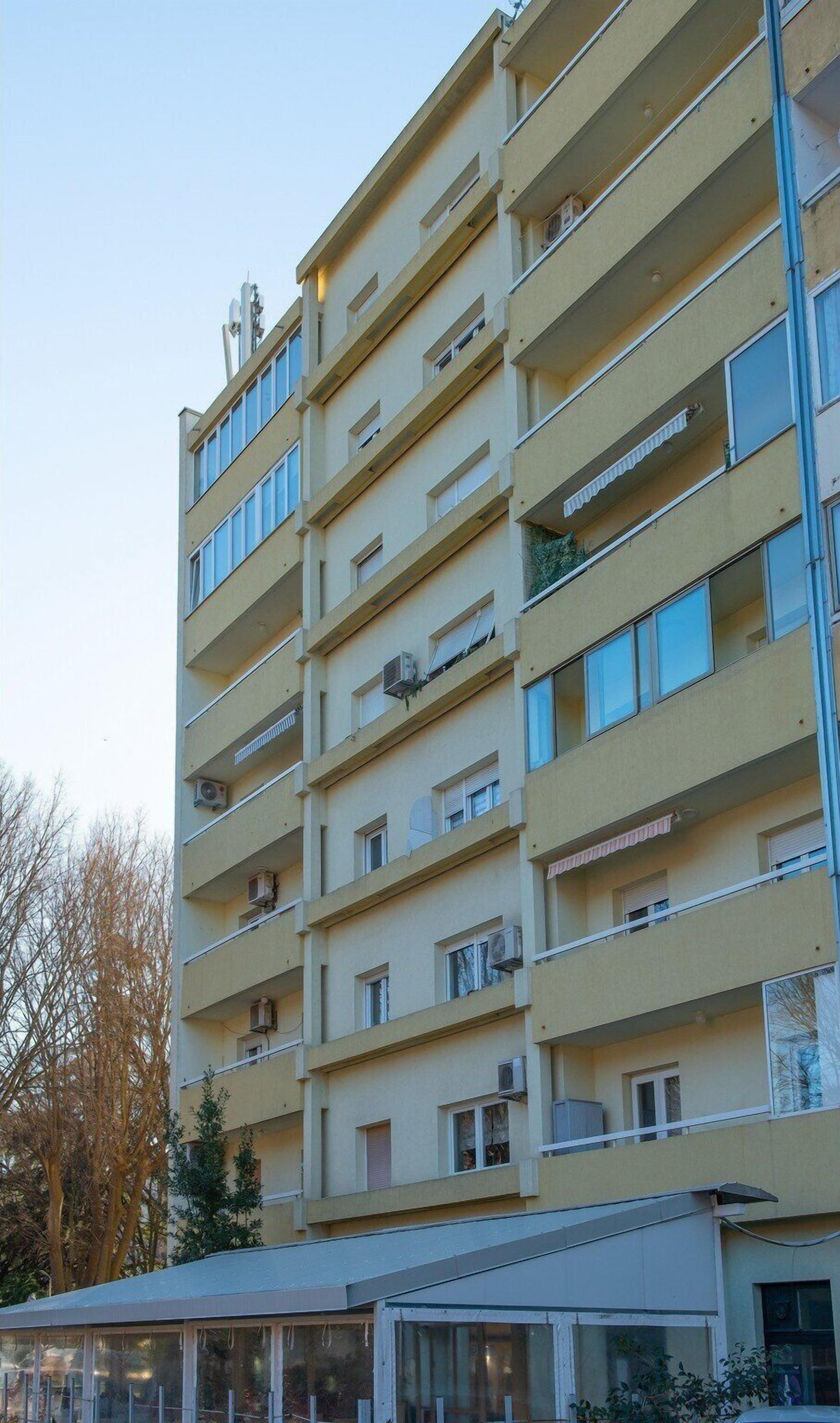 Un immeuble résidentiel à plusieurs étages, doté de balcons, de climatiseurs et d’une façade plane.