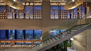 A modern interior with a staircase, seating area, and large windows offering city views. - OMO5 Okinawa Naha by Hoshino Resorts (Naha)