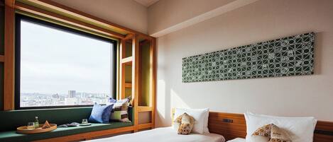 A hotel room with two beds, a window with a view of the city, a green wall, and a geometric patterned artwork.