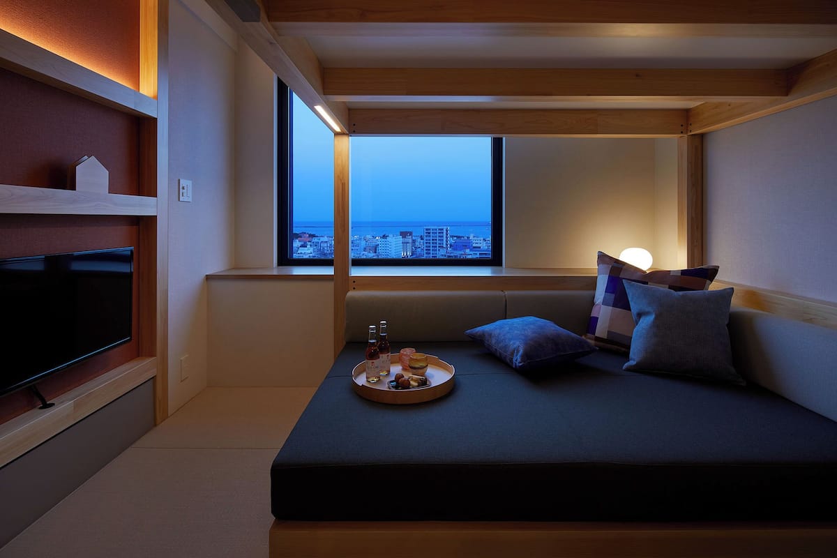 Une chambre confortable avec un lit, une télévision et une fenêtre donnant sur la ville.