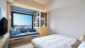 A modern bedroom with a large window, built-in seating area, and a bed.