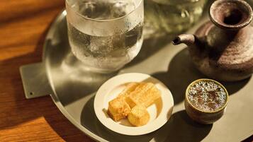 Una bandeja con un vaso de agua, un plato pequeño con dos cubitos de hielo y una taza con una bebida espumosa.