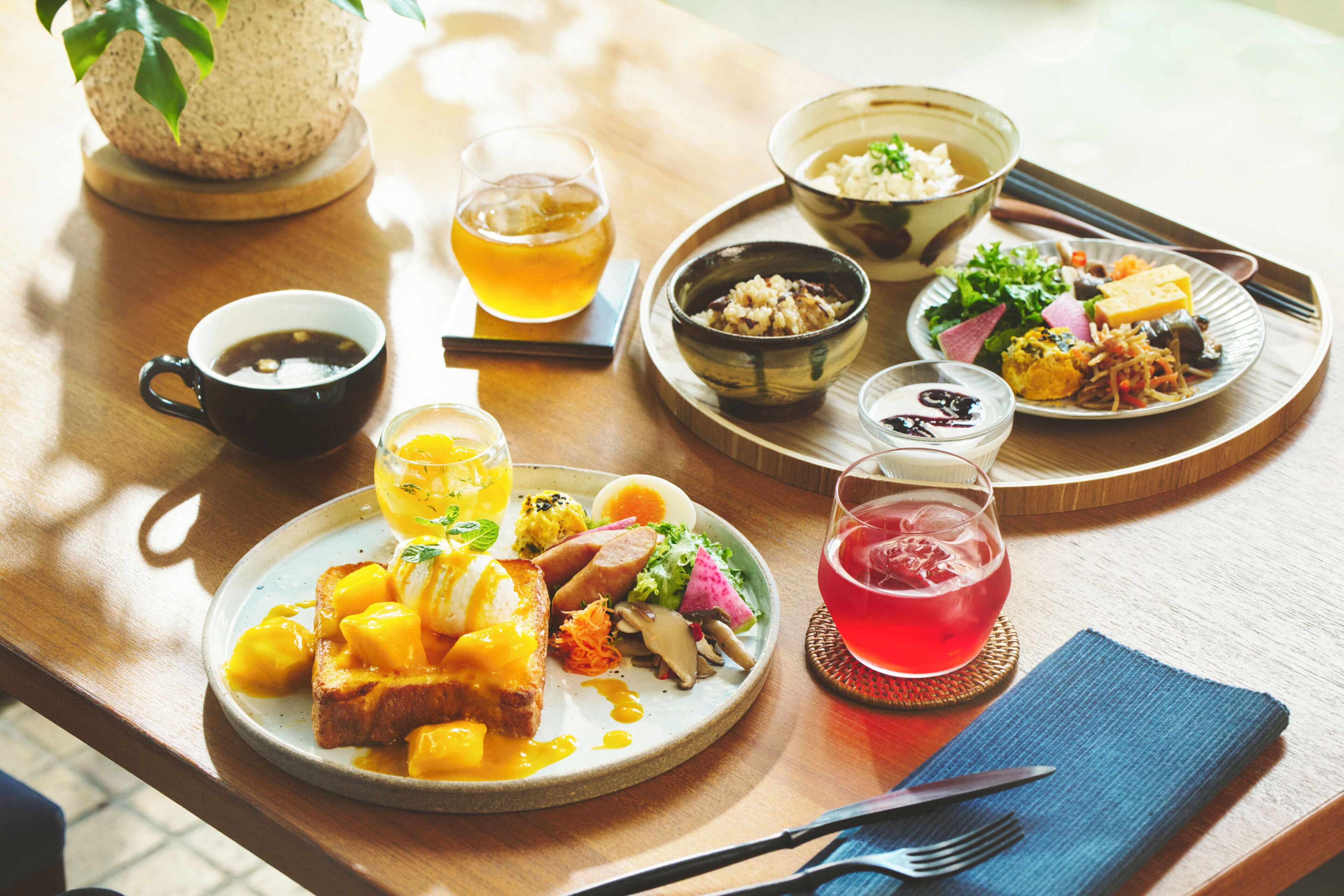 A wooden table with various dishes, including a plate of toast, a bowl of salad, and a glass of red drink.