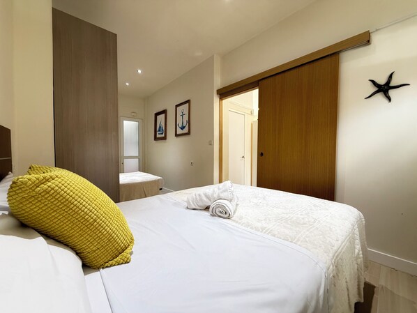 A hotel room with a bed, a yellow pillow, a white towel, a starfish decoration, and a wooden wardrobe.