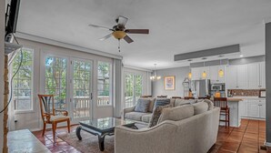 A spacious living room with a sofa, a coffee table, and a dining area with a chair and table. There is a kitchen area with cabinets and appliances. - 4 Mizzenmast Court at The Sea Pines Resort (Hilton Head Island)
