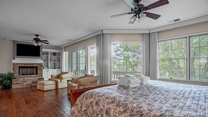 A spacious bedroom with a large bed, a fireplace, a TV, and a ceiling fan. - 4 Mizzenmast Court at The Sea Pines Resort (Hilton Head Island)