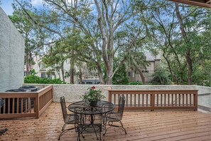 An outdoor patio with a round table and chairs, surrounded by a wooden deck and a white wall. - 4 Mizzenmast Court at The Sea Pines Resort (Hilton Head Island)