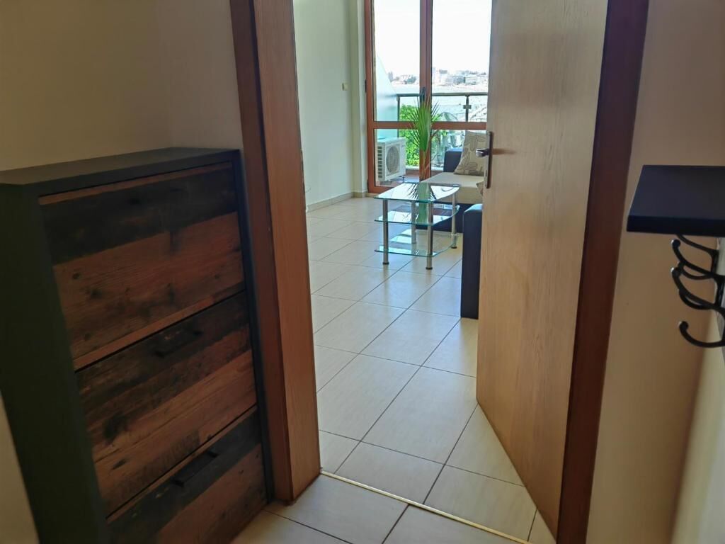 Una habitación con un armario de madera, una mesa de vidrio y vistas a un balcón con una planta.