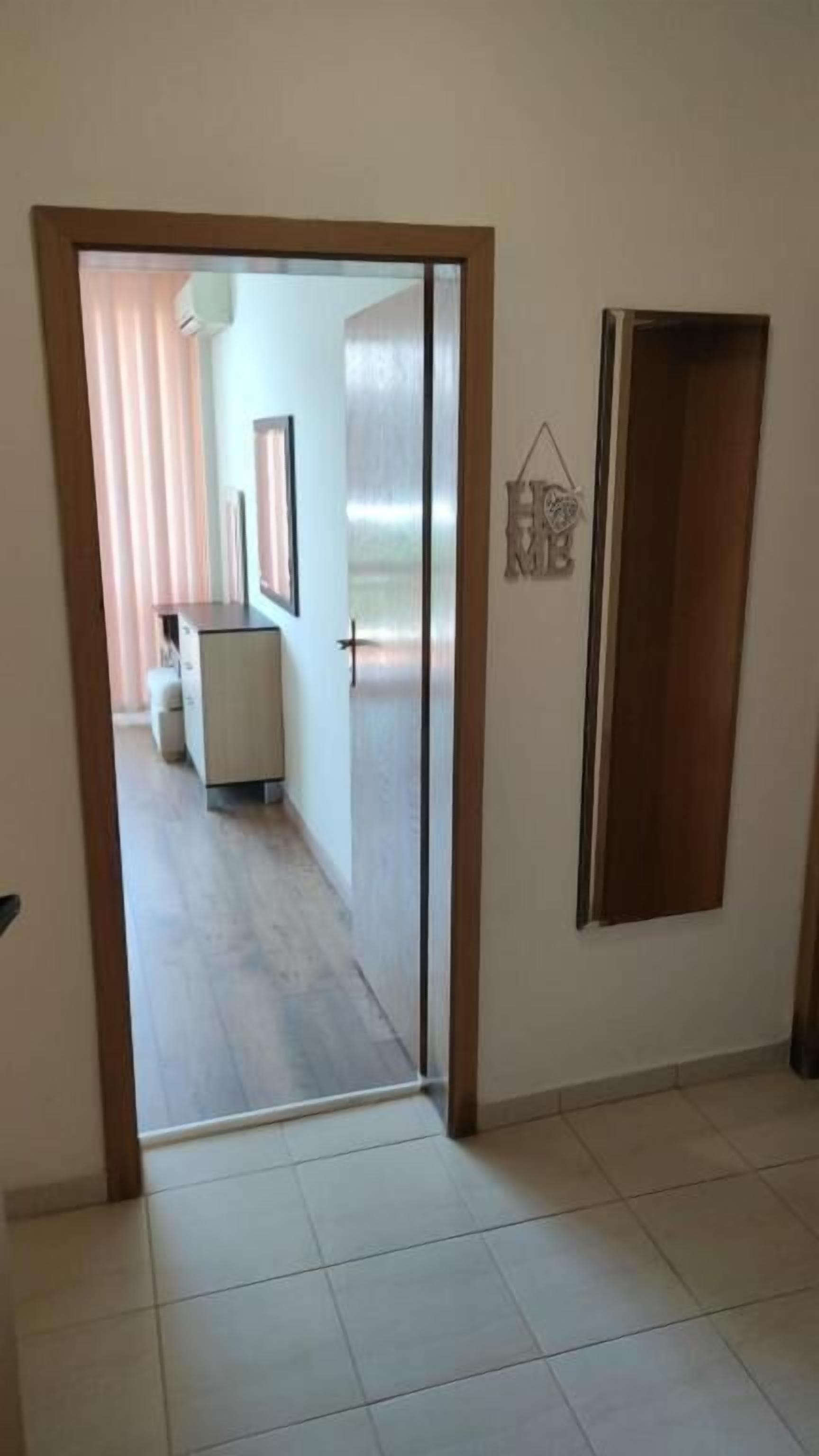 Un pasillo con piso de baldosas, un armario blanco y una puerta decorada con un corazón.