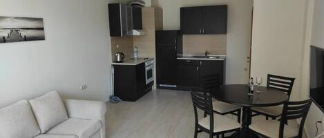 Un espacio habitable compacto con kitchenette, comedor y sofá.