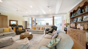 A spacious living room with a beige sofa set, a coffee table, and a wooden cabinet with decorative items.