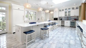 A modern kitchen with white cabinetry, a central island with bar stools, and pendant lighting.