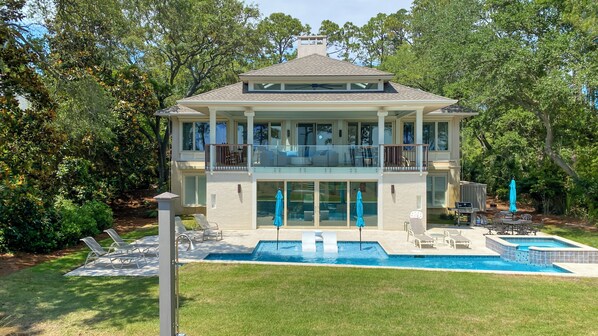 A two-story house with a large balcony, a swimming pool, and outdoor furniture.