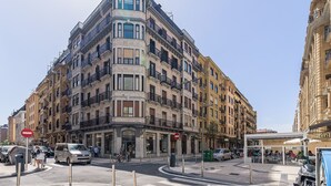 A multi-story building with a corner entrance, balconies, and a pedestrian area with outdoor seating. - Free Soul by FeelFreeRentals (San Sebastian)