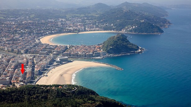 An aerial view of a coastal city with a beach, a peninsula, and a bridge connecting the mainland to the peninsula. - Free Soul by FeelFreeRentals (San Sebastian)