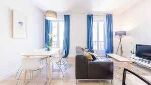 A modern living room with a sofa, a dining table, and a TV. - Free Soul by FeelFreeRentals (San Sebastian)