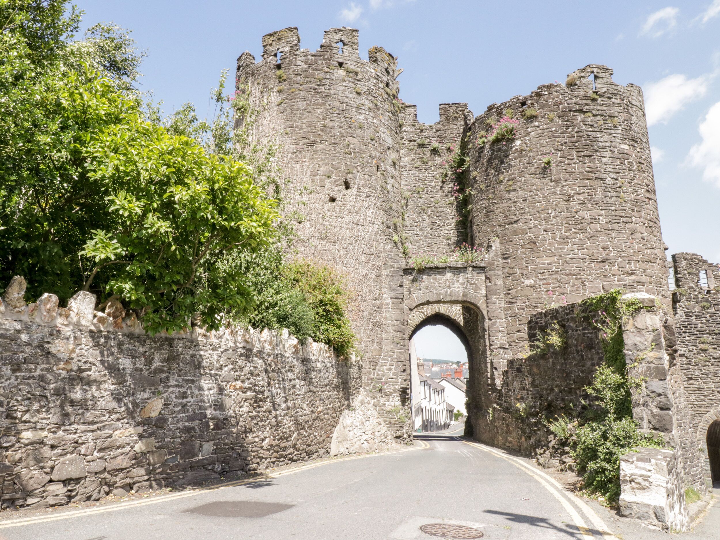 Une entrée de château en pierre, avec une route qui la traverse.
