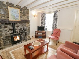 Una sala de estar acogedora con chimenea de piedra, televisor, sillón mullido y una mesa de centro.