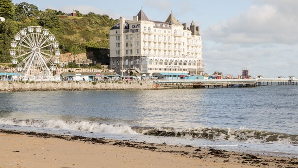 A coastal hotel with a large Ferris wheel and a pier extending into the water. - Tudor Cottage (Conwy)