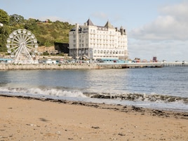Un hotel frente al mar con una noria grande y un muelle que se adentra en el agua.