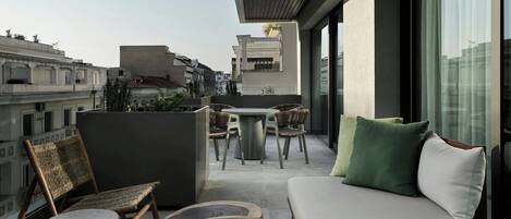 A modern balcony with a sofa, chairs, and a dining table.