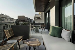 Un balcón moderno con sofá, sillas y una mesa de comedor.