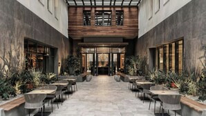 A modern indoor courtyard with a central open space, surrounded by seating areas and potted plants. - MonAsty, Thessaloniki, Autograph Collection (Thessaloniki)
