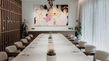 Ein Konferenzraum mit langem Tisch, Stühlen und einem großen Wandgemälde.