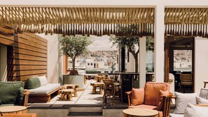 Un espace extérieur aménagé avec du mobilier en bois, un escalier menant à un niveau supérieur et une vue sur le paysage urbain.