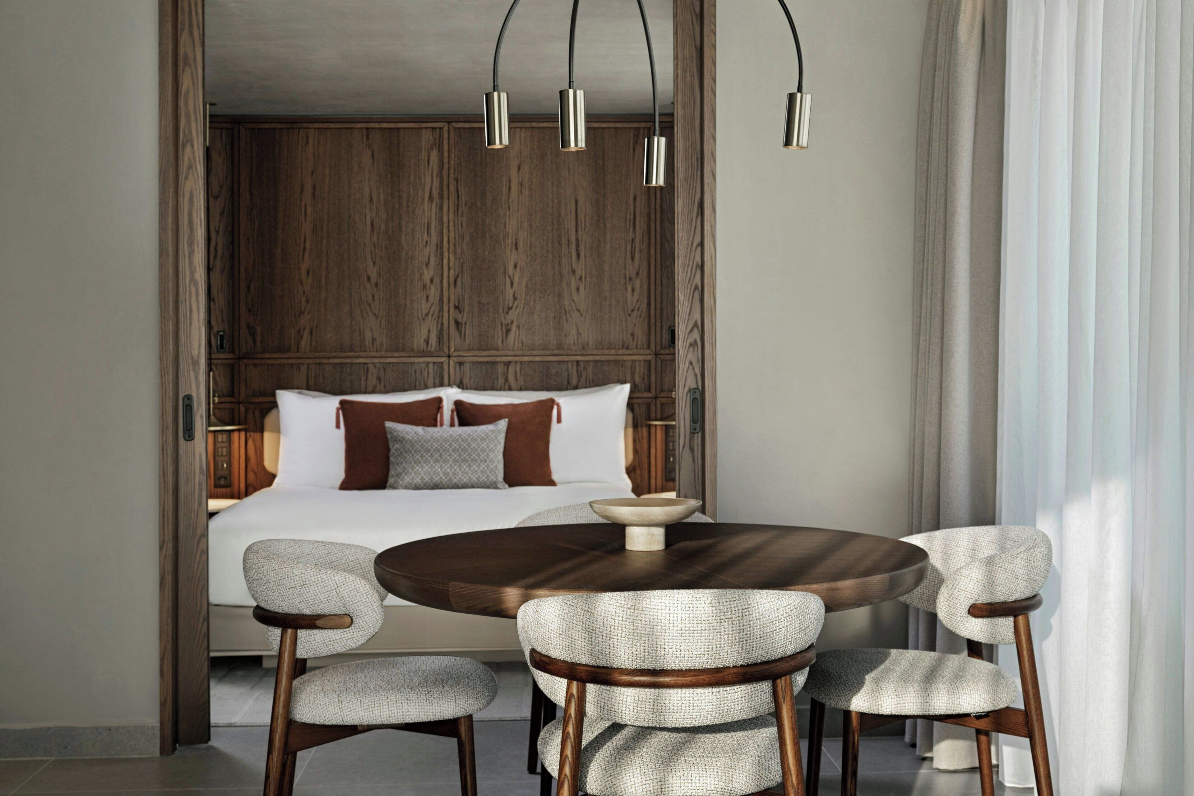Un dormitorio con una cama grande, una mesa redonda de madera con sillas y un cabecero de madera.