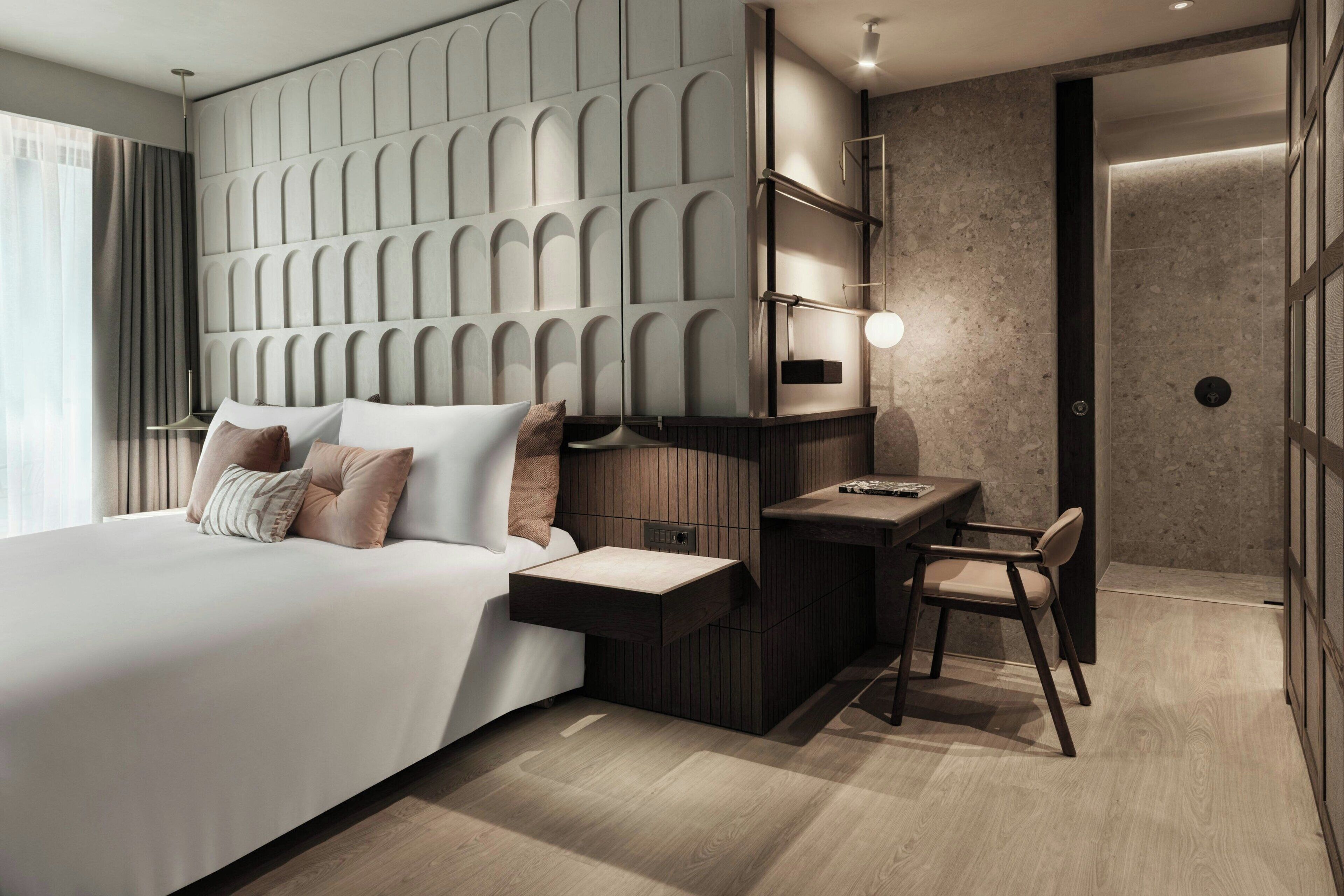 Una habitación de hotel moderna con una cama grande, un escritorio y una silla.
