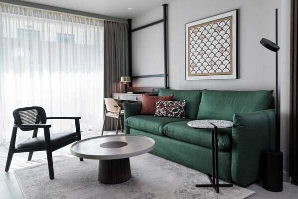 A modern living room with a green sofa, a round coffee table, a black chair, and a small side table.
