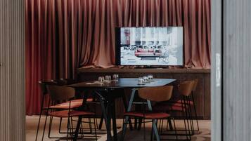 A conference room with a large table, six chairs, and a television screen displaying an image.