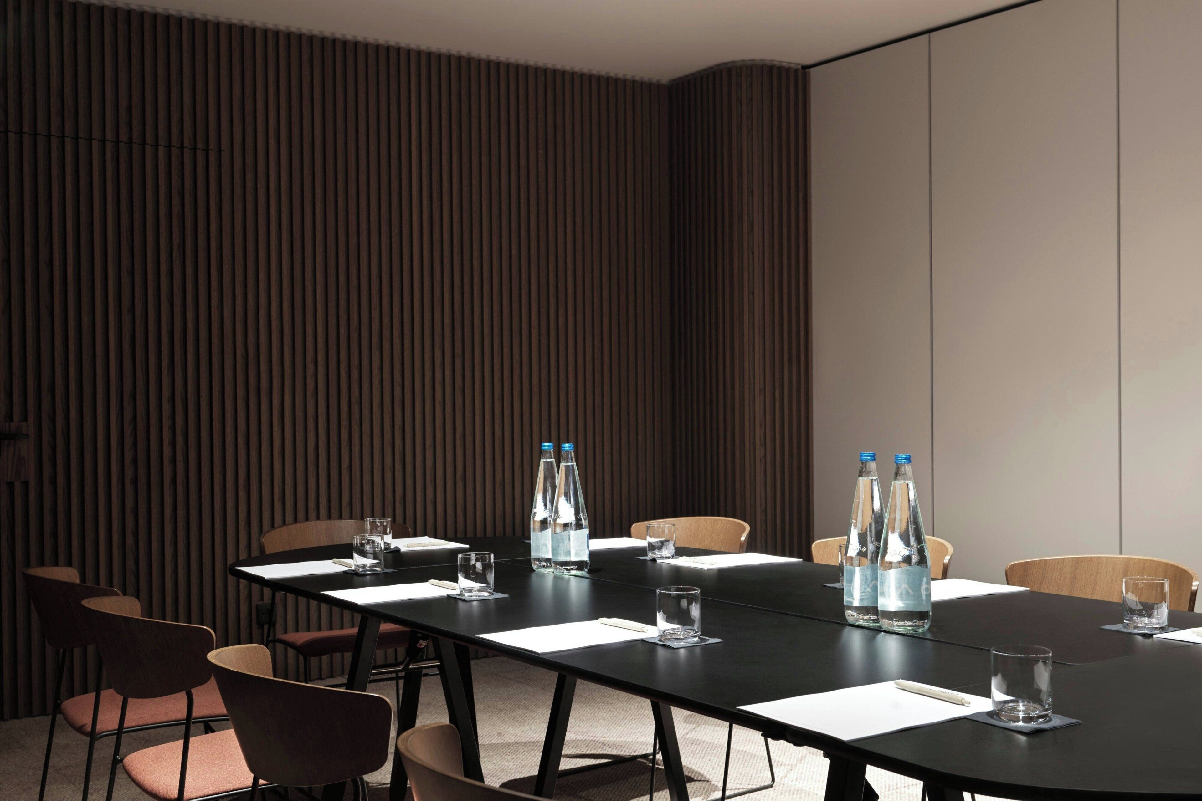 A conference room with a long table, chairs, water bottles, and glasses.